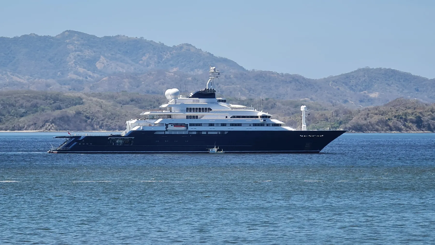 A large motor yacht at anchor in a calm bay with forested hills behind, Guanacaste